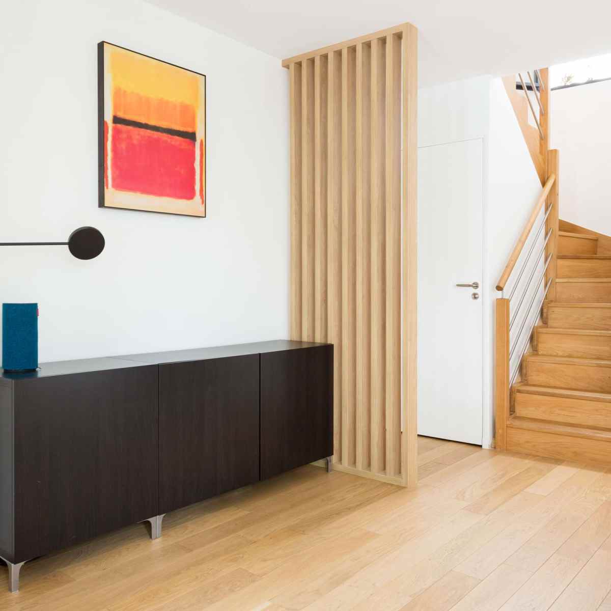Le claustra bois sur mesure installé dans cet appartement, permet de créer un espace pour l'entrée