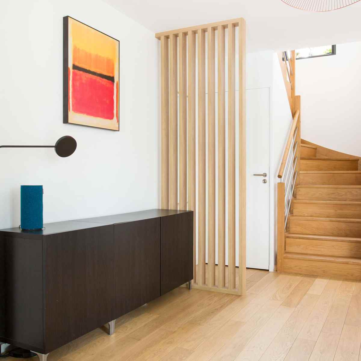Ce claustra bois d'intérieur sur mesure permet de définir clairement l'entrée de cet appartement à Paris
